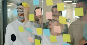 Diverse team brainstorming with colorful sticky notes on glass in modern office.