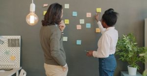 Collaboration in an office setting with a diverse team using sticky notes for brainstorming.