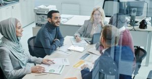 A diverse group of professionals engaged in a meeting at a modern office, promoting teamwork and collaboration.