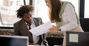 Business professionals in a discussion, reviewing documents in a modern office setting.