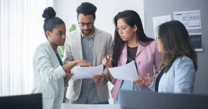 A diverse group of professionals engaged in a focused team meeting within an office environment.